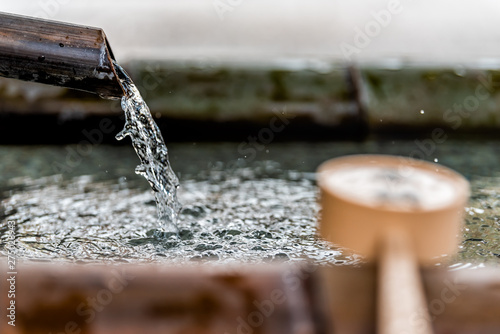 Purification fountain in Kyoto, Japan with bamboo ladle and water running from spout