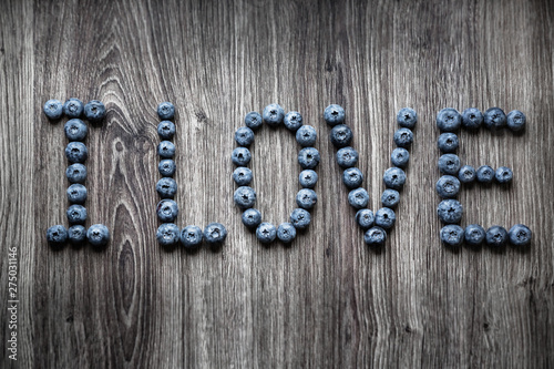 Ripe tasty blueberries and berries on a wooden table with I love words
