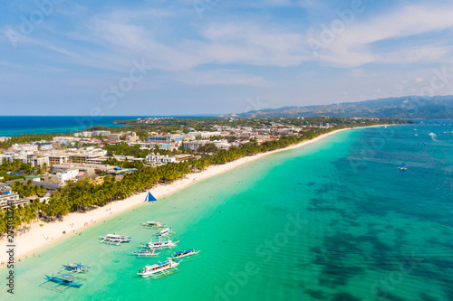 Island Boracay, Philippines, view from above. White beach with palm trees and turquoise lagoon with boats. Buildings and hotels on the big island.