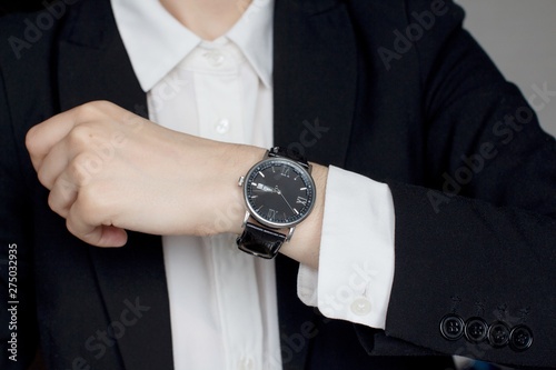 young woman in a white shirt and black suit wearing men's wristwatch