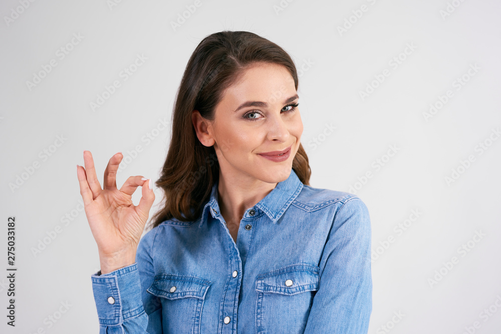 Smiling woman showing ok sign in studio shot Smiling woman showing ok sign in studio shot