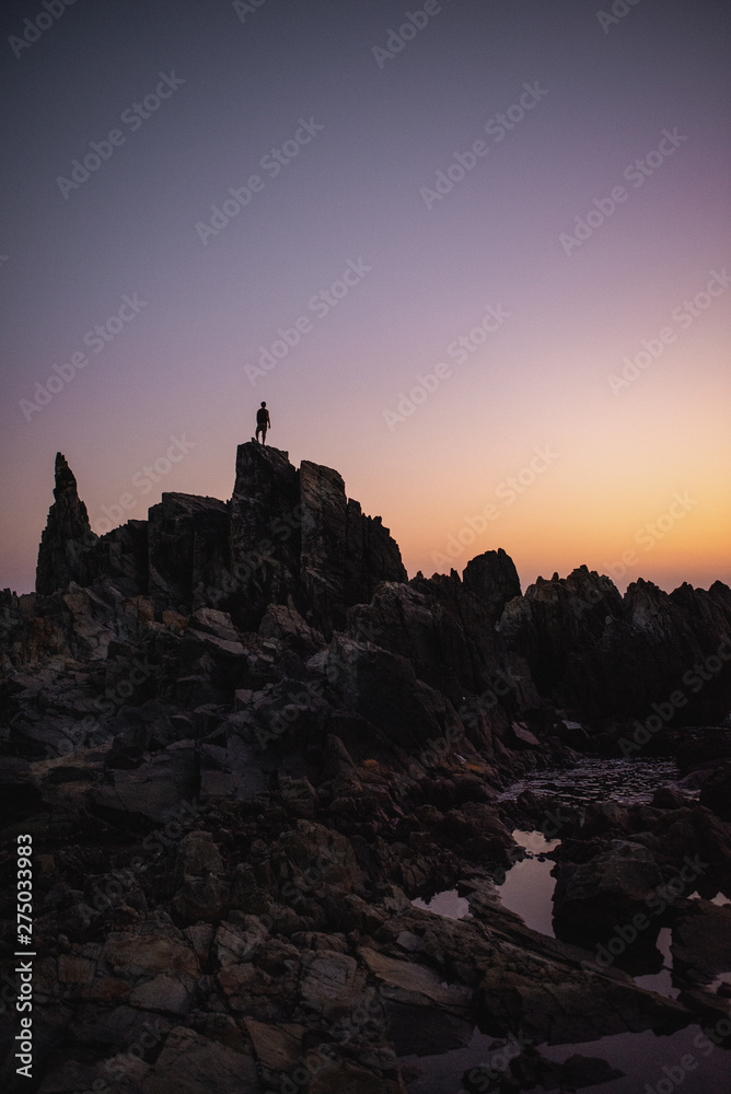 silhouette of a man at sunset standing on top of a sharp rock in a circle of large stones