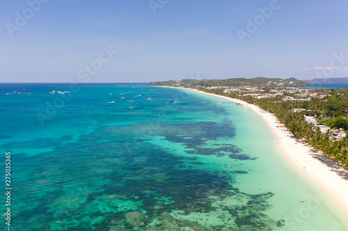 Seascape in the Philippines in sunny weather, view from above. Transparent sea and tourist boats near the island of Boracay. Residential buildings and hotels on the big island. © Tatiana Nurieva