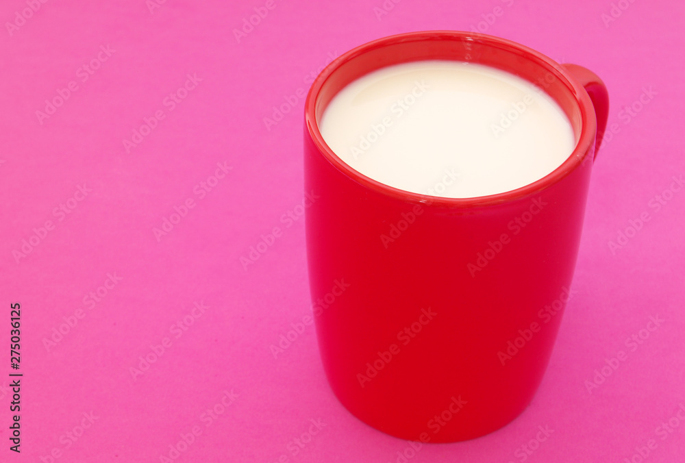 Red cup of milk on pink background with space for text Red cup of milk on pink background with space for text