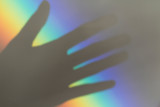 grey shadow of palm of woman's hand on rainbow background