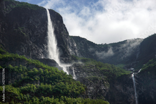 Travel to Norway  a waterfall flows from the top of a high mountain against a cloudy sky