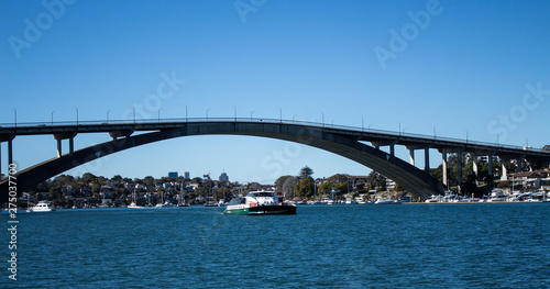 Gladesville Bridge spanning Parramatta River off Sydney Harbour with Rivercat Ferry travelling upstream, many pleasure boats on water against clear blue sky