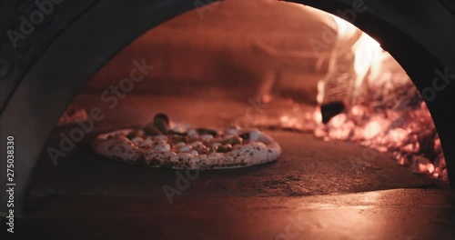 Hot steaming pizza being cooked in a brick oven wood fired. Authentic Neapolitan Pizza cooked in a wood fire oven.