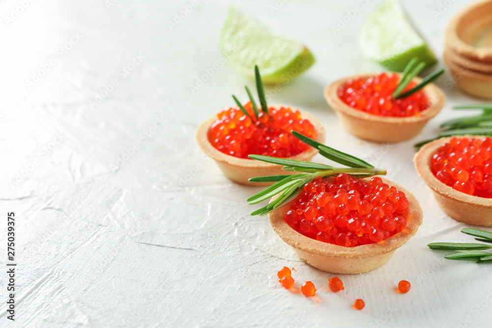 Tartlets with caviar and rosemary on white table, space for text Tartlets with caviar and rosemary on white table, space for text