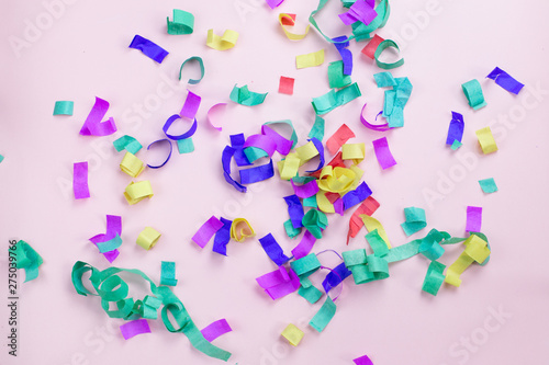 Multicolored paper confetti on a pink background. Party and holiday concept