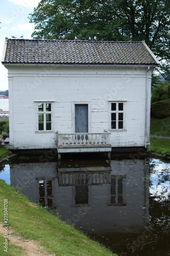 Travel to Norway, a small white house is reflected in the pond