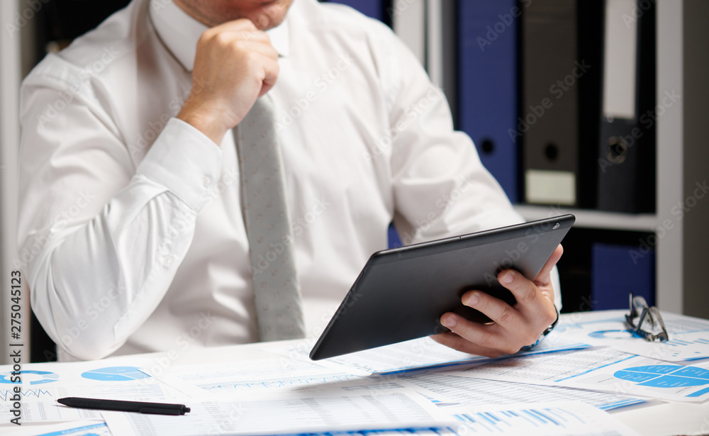Businessman working with tablet pc, calculating, reading and writing reports. Office employee, table closeup. Business financial accounting concept. Businessman working with tablet pc, calculating, reading and writing reports. Office employee, table closeup. Business financial accounting concept.