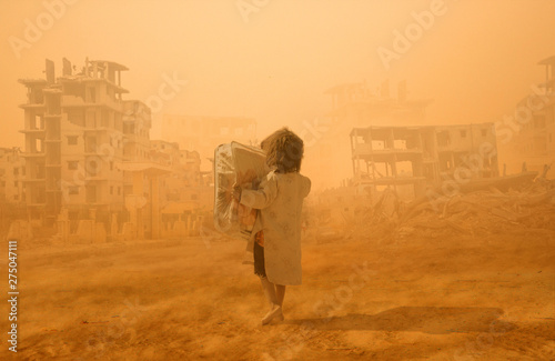 Homeless little girl walking in destroyed city that was bombed by the enemy and she's looking for shelter.