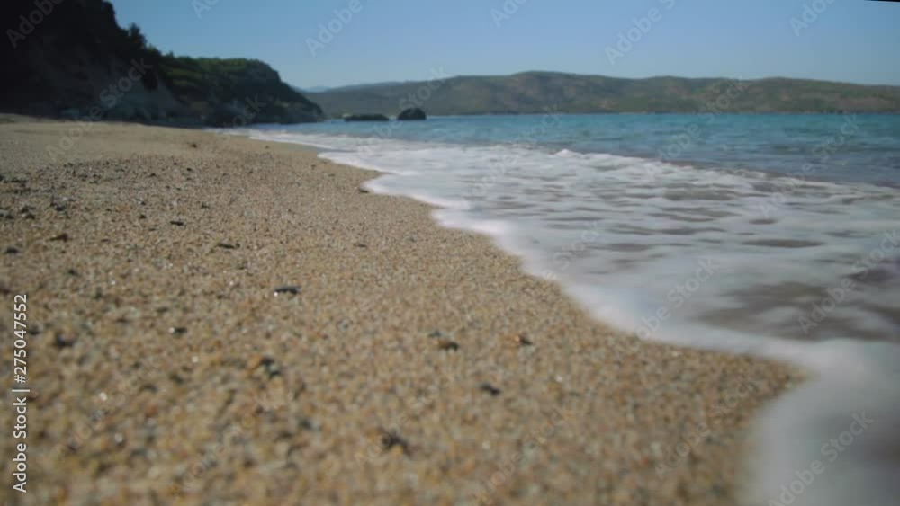 Small waves wash up on shoreline of beautiful sandy beach in Mediterranean Sea, looking along the sea towards mountain in background, sandy beach. Small waves wash up on shoreline of beautiful sandy beach in Mediterranean Sea, looking along the sea towards mountain in background, sandy beach.