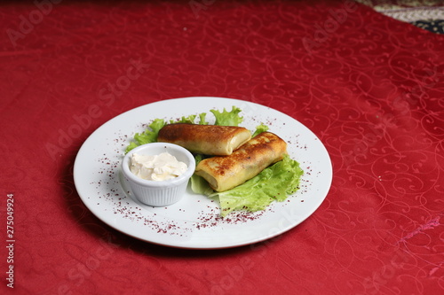 Blinchik, crepes stuffed with meat, potatoes, eggs and served with yogurt sauce and lettuce. photo