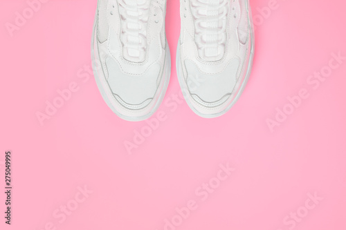 Pair of white female trendy sneakers on pink. Flat lay, top view minimal background.