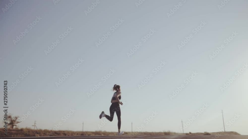 Slow motion . Girl running on the road, playing sports. runs away into the distance Slow motion . Girl running on the road, playing sports. runs away into the distance