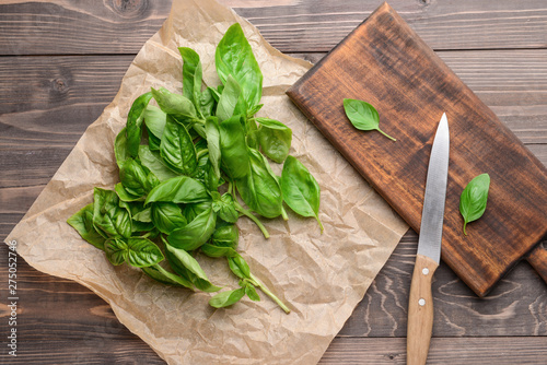 Board with fresh basil and knife on wooden table