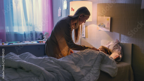 Young Loving Mother Tucks in Her Cute Little Daughter and Says 