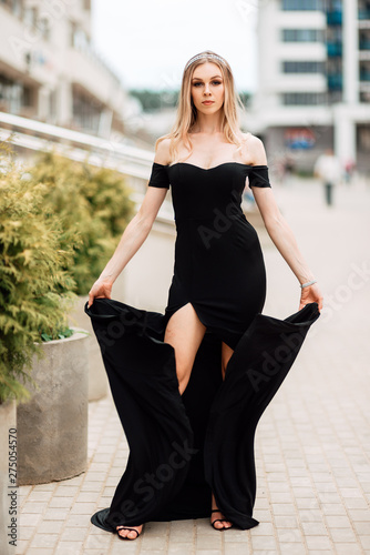 beautiful young girl in black dress walking the streets of the city, the woman is resting outdoors, street fashion. urban lifestyle.