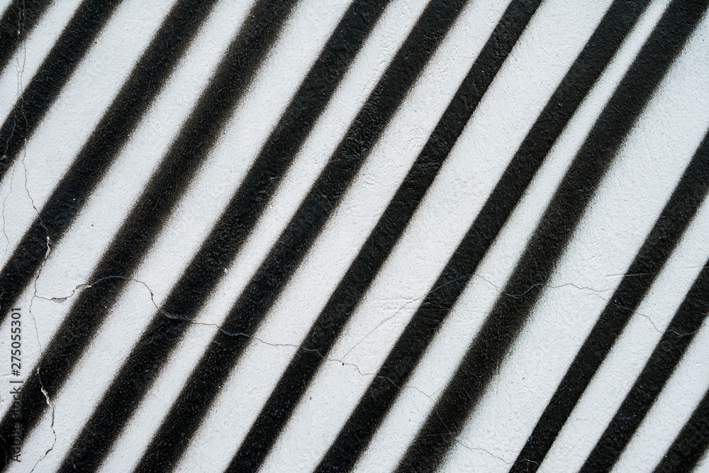 Diagonally painted surface of wall in black and white color, as graffiti. Old concrete surface with peeling paint. Graphic grunge texture of wall. Abstract background Diagonally painted surface of wall in black and white color, as graffiti. Old concrete surface with peeling paint. Graphic grunge texture of wall. Abstract background