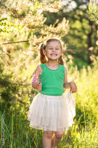 little girl with flowers bells on nature in summer