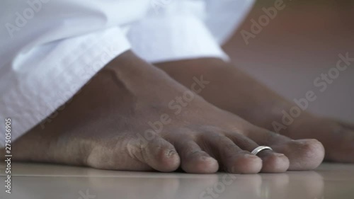 Handheld, close up shot of bare feet, a toe ring is on the index toe.
