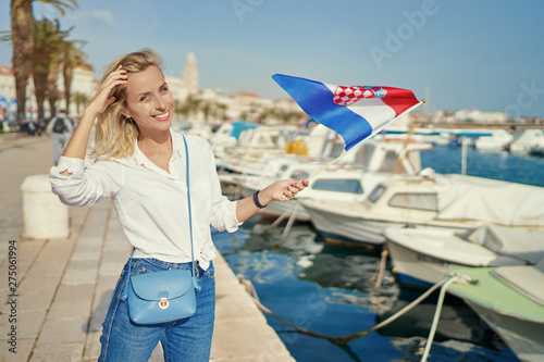 Enjoying vacation in Croatia. Young traveling woman with national croatian flag walking on Split sea shore promenade. © luengo_ua
