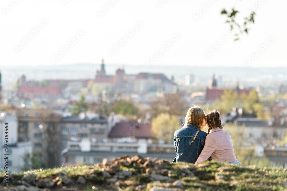 Female couple from behind on Krakus mound with a view at Wawel castle on background.