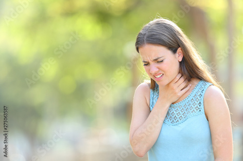 Woman suffering sore throat in a park
