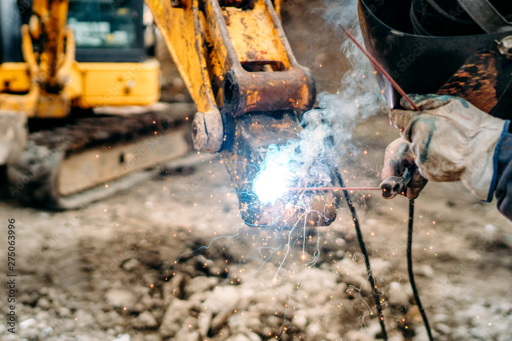 Fototapeta premium close up of welding details, sparks on construction site excavator