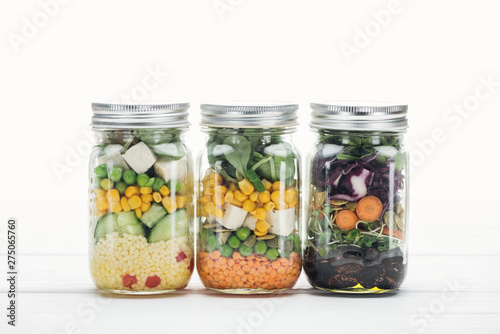 delicious fresh vegetable salad in glass jars isolated on white