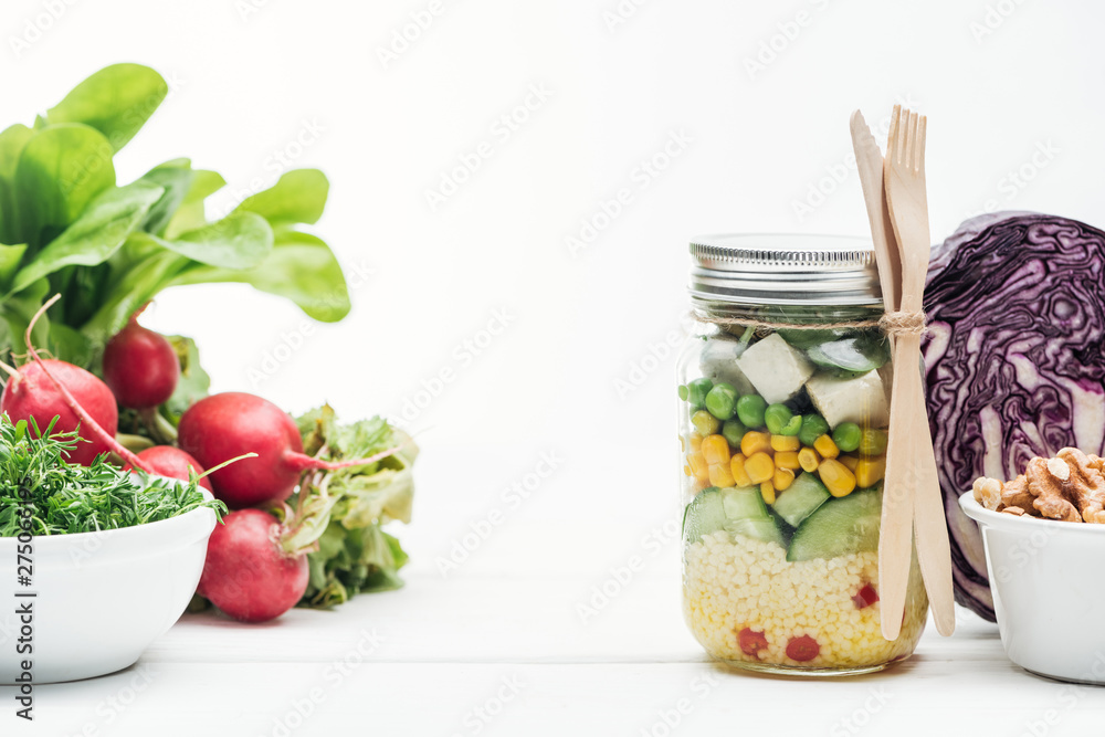 fresh vegetable salad in glass jar near radish, red cabbage and nuts isolated on white fresh vegetable salad in glass jar near radish, red cabbage and nuts isolated on white