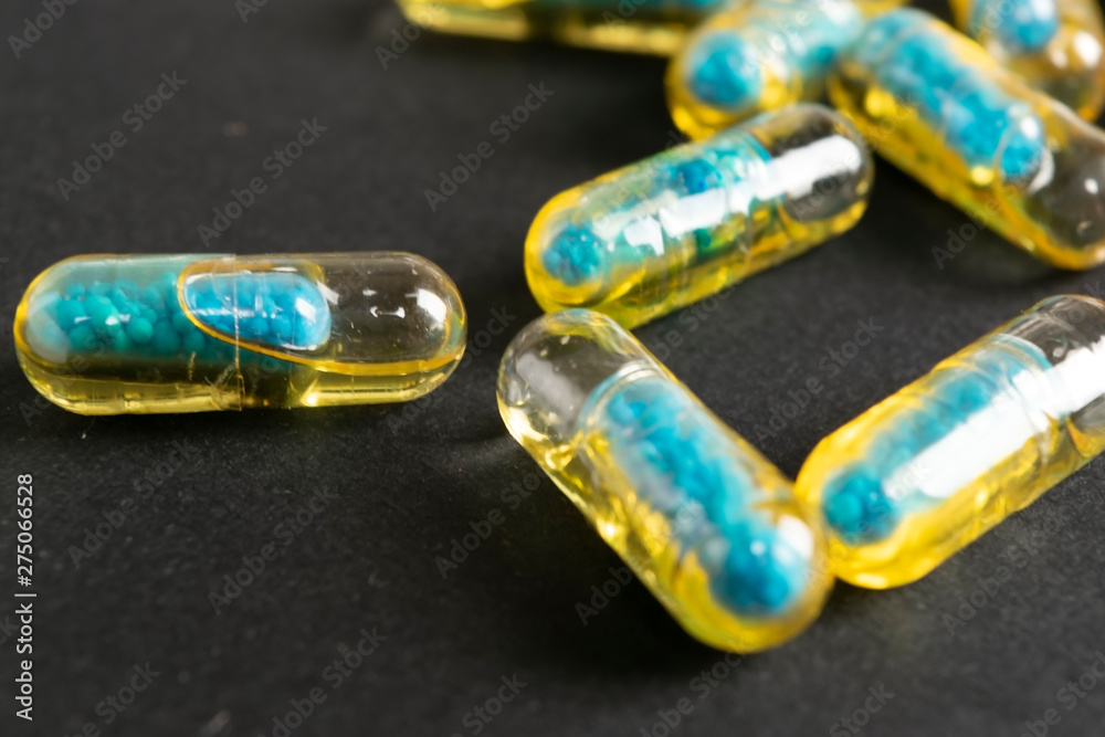 Gelatin capsules with the medicine are scattered across the table. Gelatin capsules with the medicine are scattered across the table.