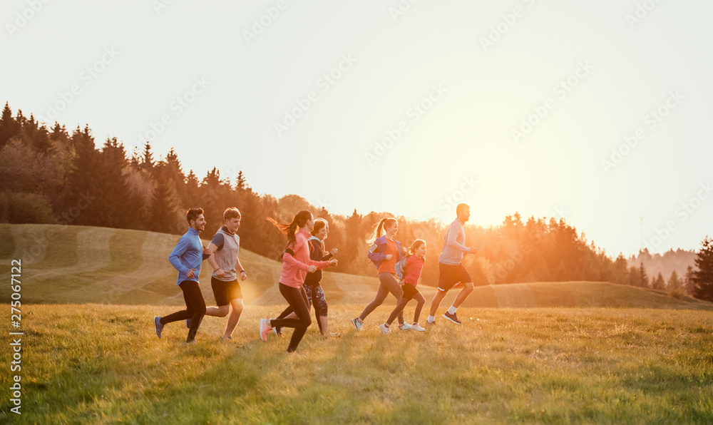 Large group of people cross country running in nature.