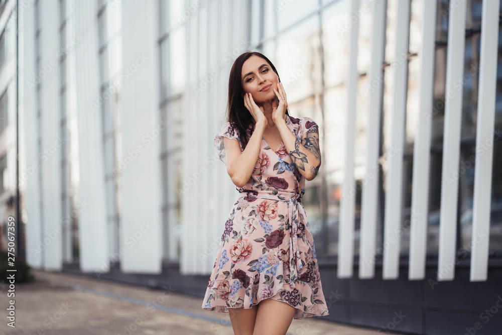 Beautiful young woman in colored dress posing near business center Beautiful young woman in colored dress posing near business center