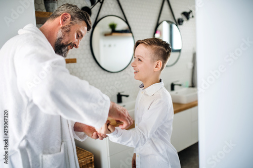 Mature father with small son getting dressed in the bathroom in the morning.