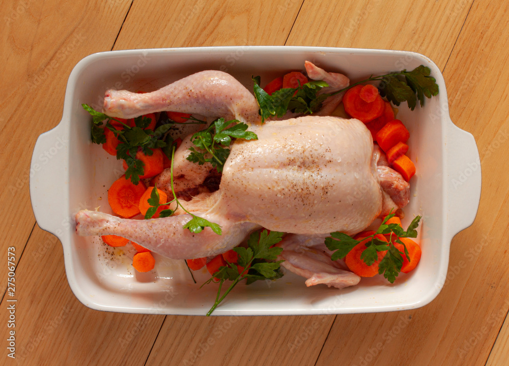 Raw chicken withwith vegetables and olive oil in a baking dish ready to be prepared for cooking. Top view image on wooden background. Raw chicken withwith vegetables and olive oil in a baking dish ready to be prepared for cooking. Top view image on wooden background.
