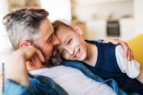 Mature father with small son sitting on sofa indoors, resting. photo