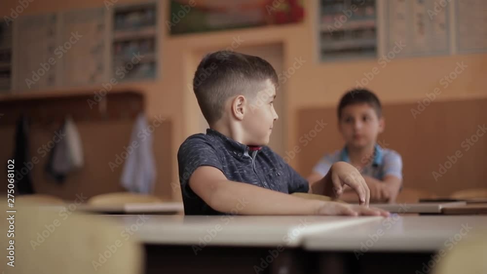 Happy little children in elementary school. Boys and girls study. Children raise hand up Happy little children in elementary school. Boys and girls study. Children raise hand up