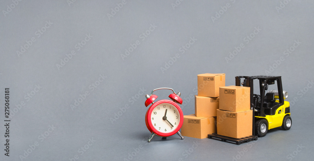 Obraz premium Yellow Forklift truck with cardboard boxes and a red alarm clock. Express delivery concept. Temporary storage, limited offer and discount. Optimization of delivery logistics. Banner, copy space