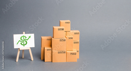 Lots of cardboard boxes and stand with green up arrow. Growth of income from the sale of goods. Price increase. The growth rate of production. Increasing consumer demand. exports and imports rise