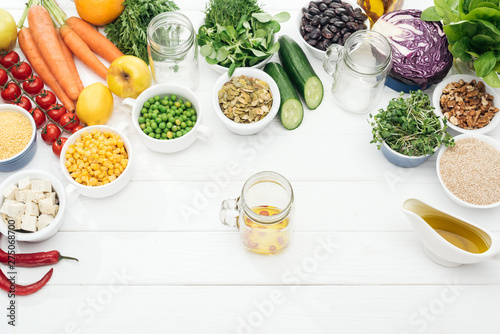 Fototapeta Naklejka Na Ścianę i Meble -  top view of glass jar with oil and chili pepper near fruits and vegetables near glass jars on wooden white table