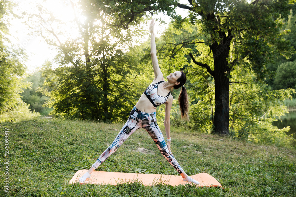 the girl is engaged in fitness and meditates in the park city