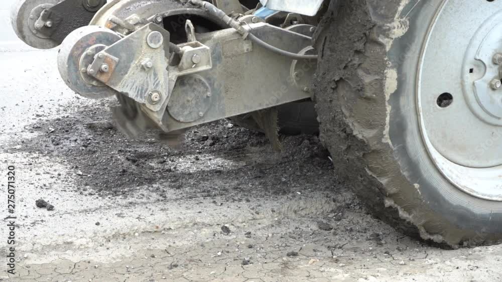 Road milling machine cuts the old asphalt. Road repair. Destruction of the road surface. The cutter cuts a layer of asphalt. Pieces of stone fly apart. Close-up Road milling machine cuts the old asphalt. Road repair. Destruction of the road surface. The cutter cuts a layer of asphalt. Pieces of stone fly apart. Close-up
