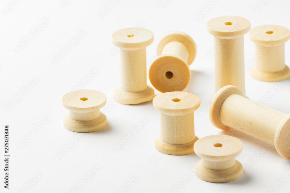 Variety of wooden thread spools of different sizes scattered on white background. Sewing crafts hobbies tailoring fashion clothes making concept. Eco nature friendly reusable materials. Zero waste Variety of wooden thread spools of different sizes scattered on white background. Sewing crafts hobbies tailoring fashion clothes making concept. Eco nature friendly reusable materials. Zero waste