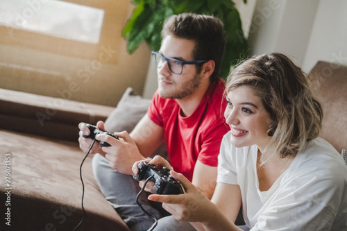 Young couple plays a video game with the console on the couch at home photo