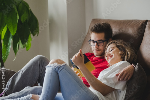 A couple reads a book on the couch at home photo