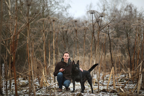 A man with a mongrel dog walking on a winter meadow