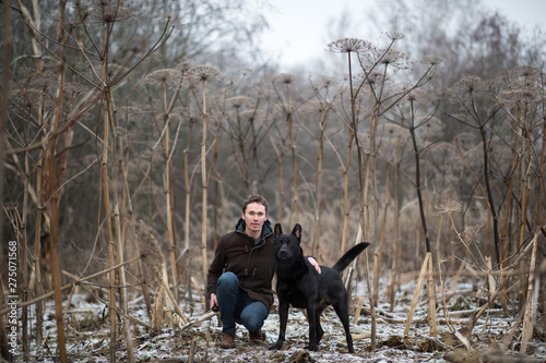 A man with a mongrel dog walking on a winter meadow © Alexandr